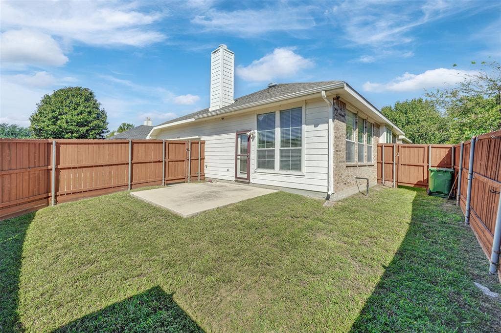 Enclosed backyard with a concrete patio, wood fencing, and a white siding exterior