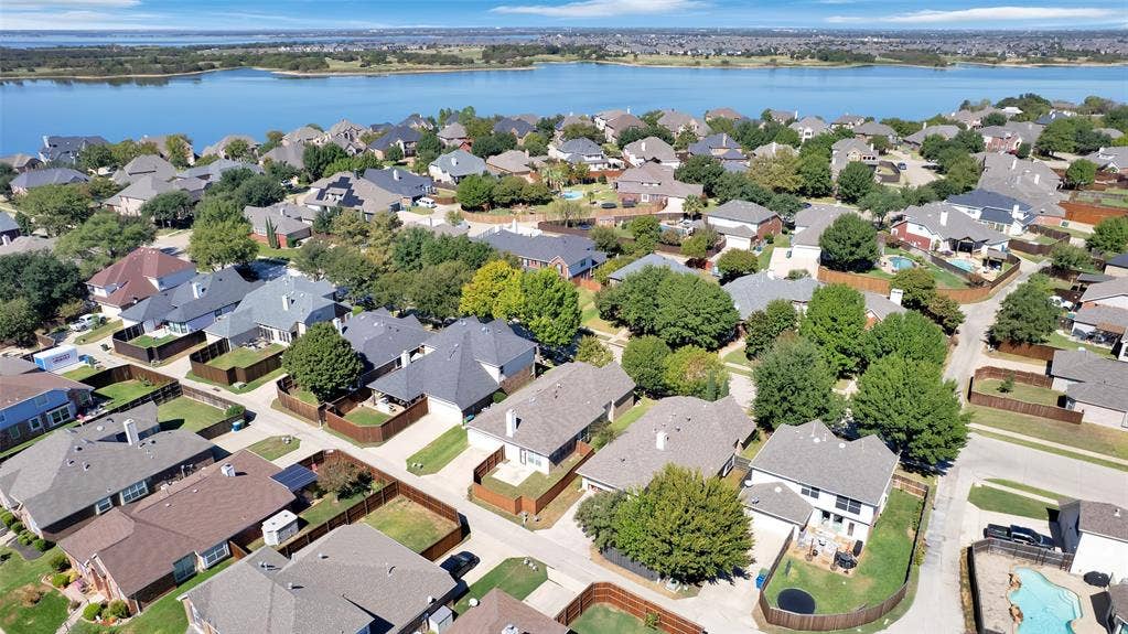 Residential community with mature trees and a substantial body of water in the background