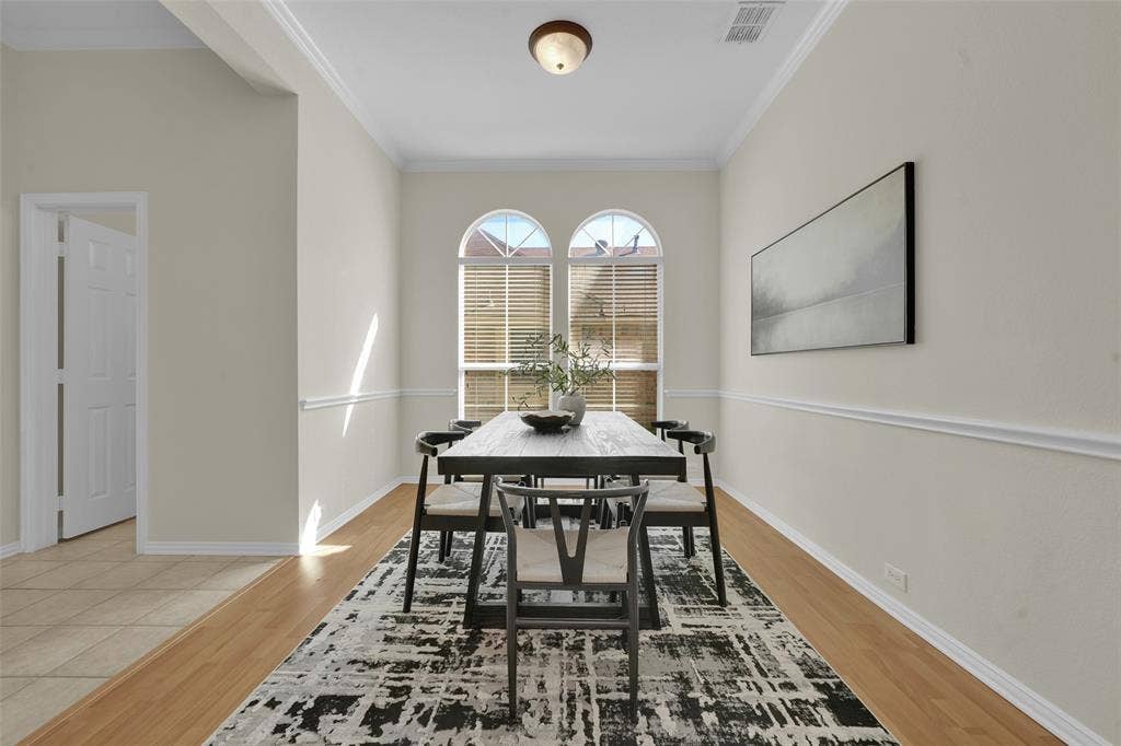 Arched windows with horizontal blinds, neutral-toned walls, wood-finish flooring, and crown molding