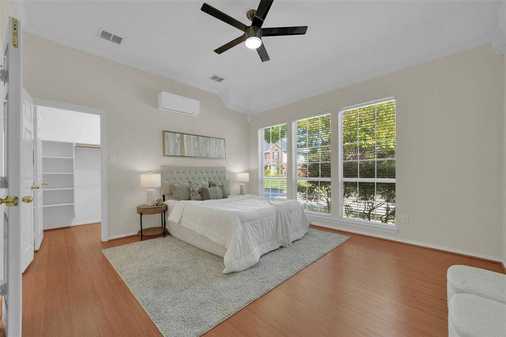 Wood-finish flooring with white baseboards, a ceiling fan, and three large windows