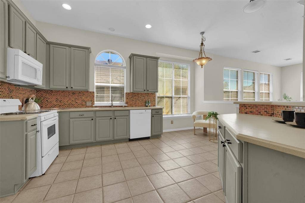 Kitchen featuring extensive cabinetry, tile backsplash, built-in appliances, recessed lighting, and a kitchen island with additional storage