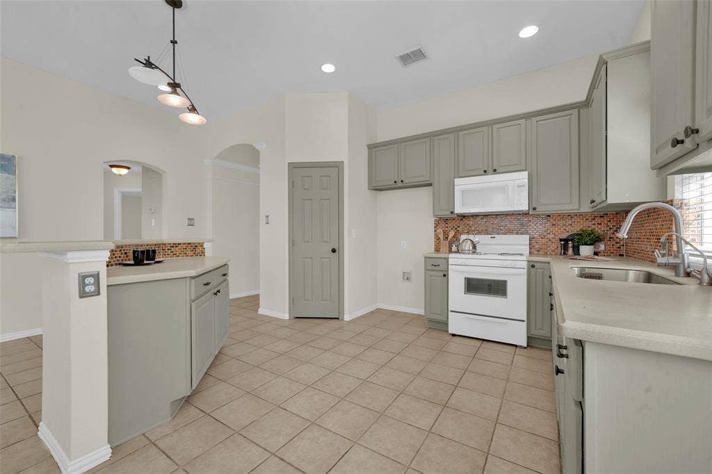 Kitchen featuring light-toned cabinetry, tile flooring, and a mosaic tile backsplash