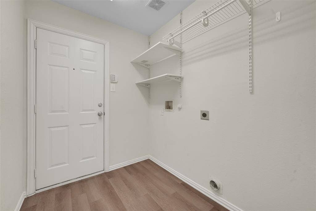 Wood-finish flooring, white paneled door, built-in shelving, and white walls