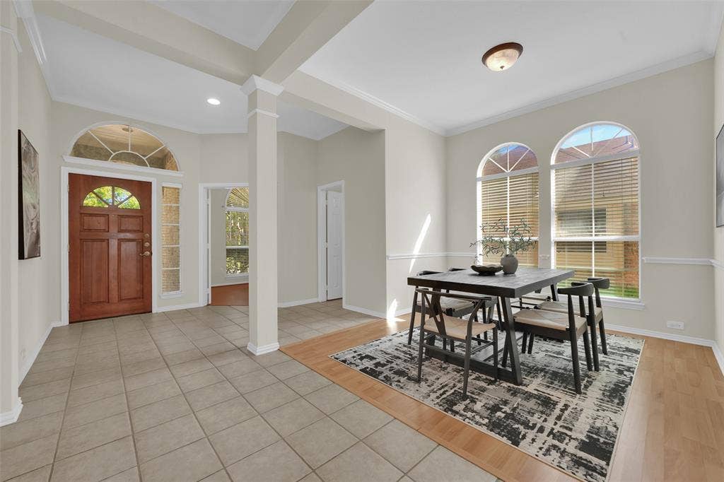 Entryway featuring a wood-panel door with an arched transom, tile flooring, and column detailing