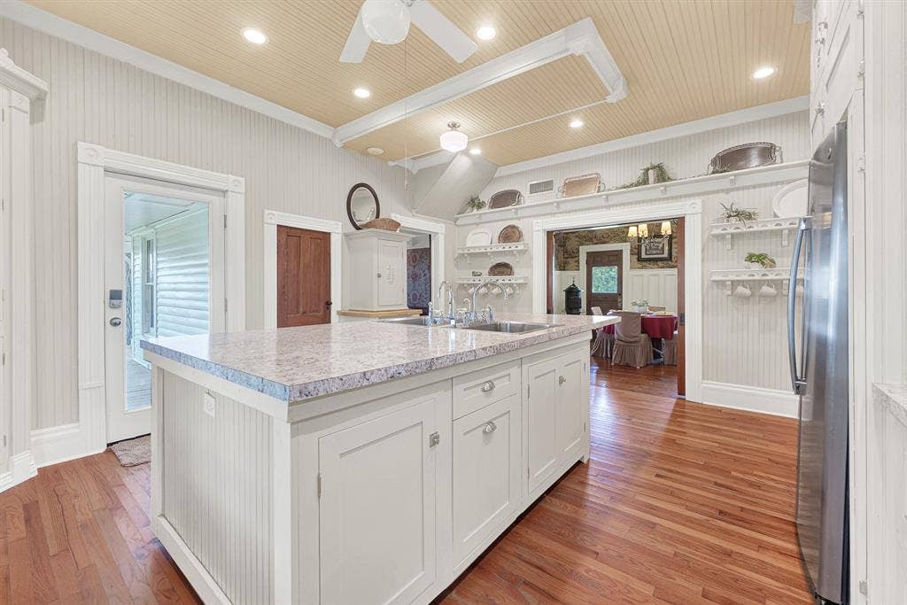 1425-1 Lone Star Road, Celina, TX 75009 The expansive island with double sinks anchors a 2022 kitchen remodel featuring updated countertops, oven, refrigerator, and dishwasher, all thoughtfully integrated into the home's Victorian character. Whether baking with grandchildren or serving a crowd during the holidays, this kitchen was made to bring people together.