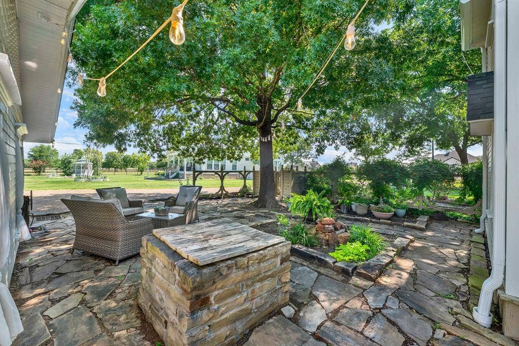 1425-1 Lone Star Road, Celina, TX 75009 Enjoy the inviting courtyard from another perspective, featuring beautiful stonework and established gardens. The expansive patio offers multiple gathering spaces, blending timeless character with relaxed outdoor living.