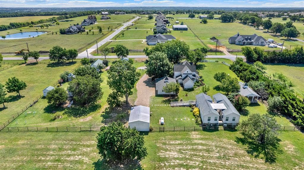 1425-1 Lone Star Road, Celina, TX 75009 This aerial showcases the timeless architecture of the beautifully restored historic residence, nestled beneath a canopy of mature trees. The wraparound porch, thoughtfully landscaped grounds, and seamless blend of original character with modern updates make this home the centerpiece of the estate. Positioned on a spacious corner lot in an area of newer luxury acreage properties, it offers both historic charm and enduring value.