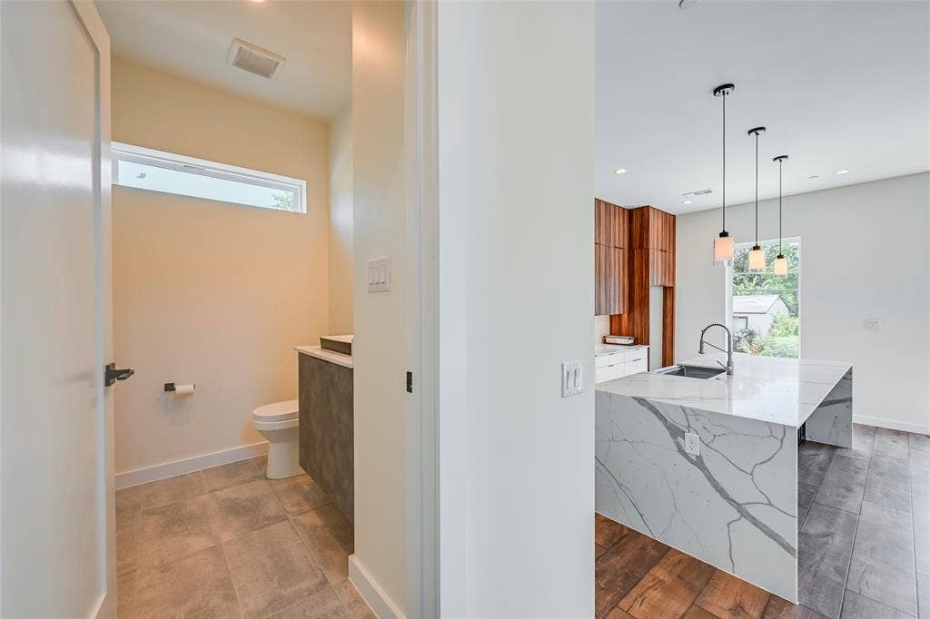 2247 Mail Avenue, #102, Dallas, TX 75235 Waterfall-edge island with integrated sink, wood-finish flooring, and pendant lighting