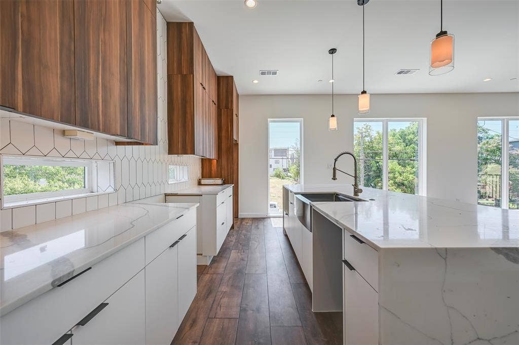 2247 Mail Avenue, #102, Dallas, TX 75235 Kitchen featuring wood-finish upper cabinetry, white lower cabinetry, white countertops, a tiled backsplash, and wood-finish flooring