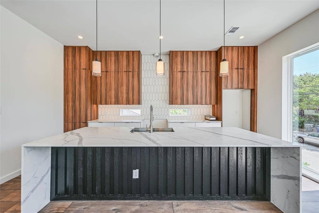 2247 Mail Avenue, #102, Dallas, TX 75235 Waterfall island with a patterned countertop, wood-finish cabinetry, recessed lighting, drop pendant lighting, and a window for natural light