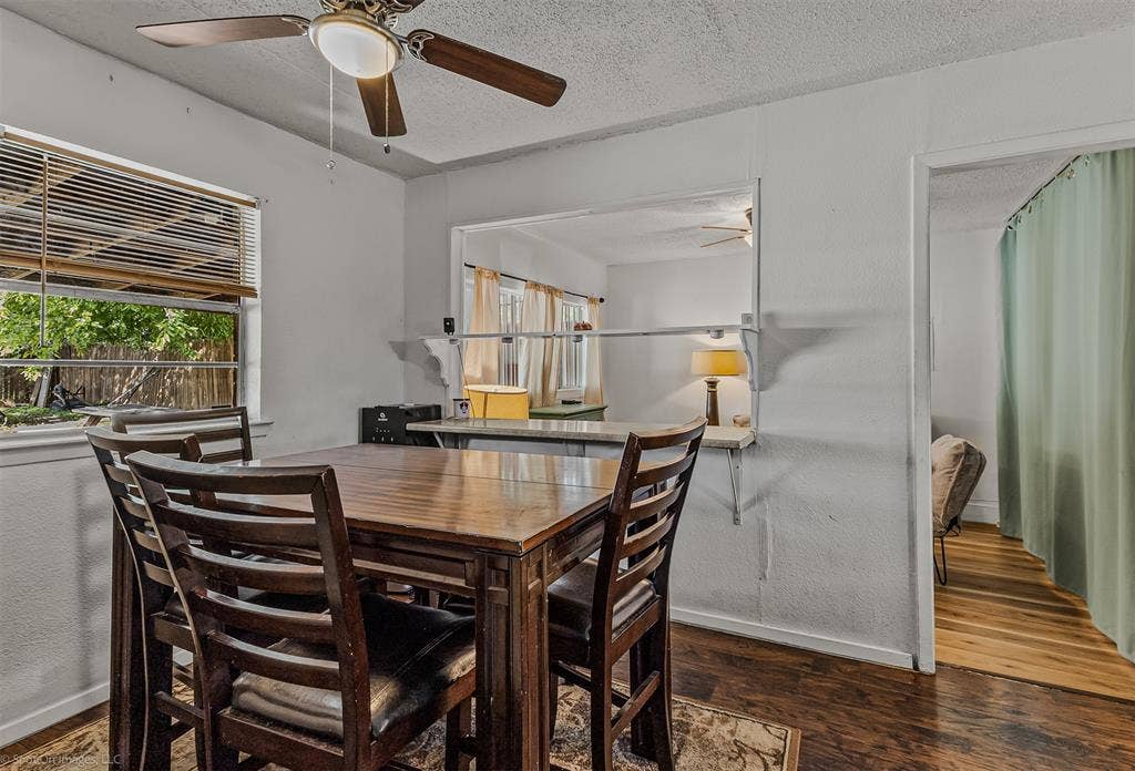 Interior space featuring wood-finish flooring, a pass-through window with a built-in counter, and a ceiling fan with integrated lighting