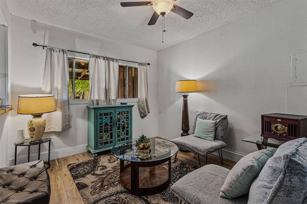 Room featuring wood-finish flooring, textured ceiling, and a ceiling-mounted fan with integrated lighting