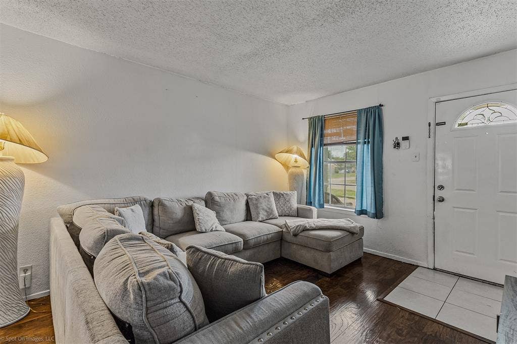 Wood-finish flooring, white entry door with a decorative arched glass pane, and ceramic tile entryway flooring