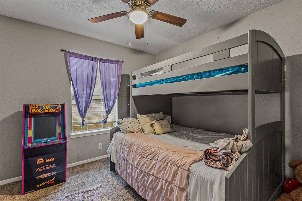 Neutral-toned wall paint, textured ceiling, carpeted flooring, and a ceiling-mounted light fixture with a fan