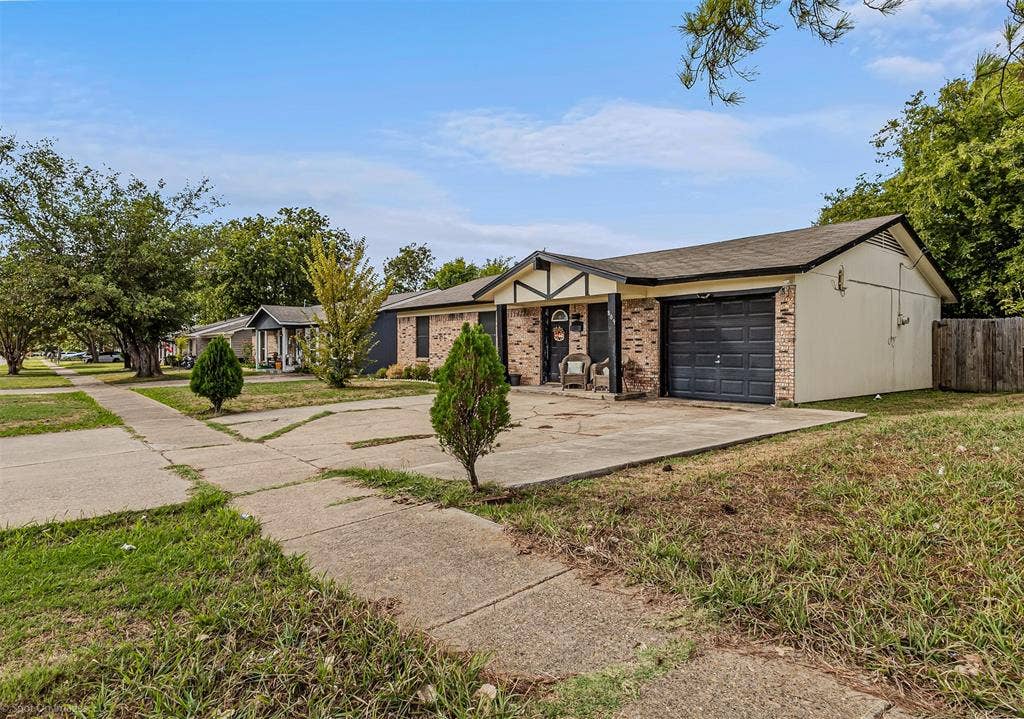 Single-story exterior featuring a brick and siding facade, covered entryway, attached garage, and concrete driveway