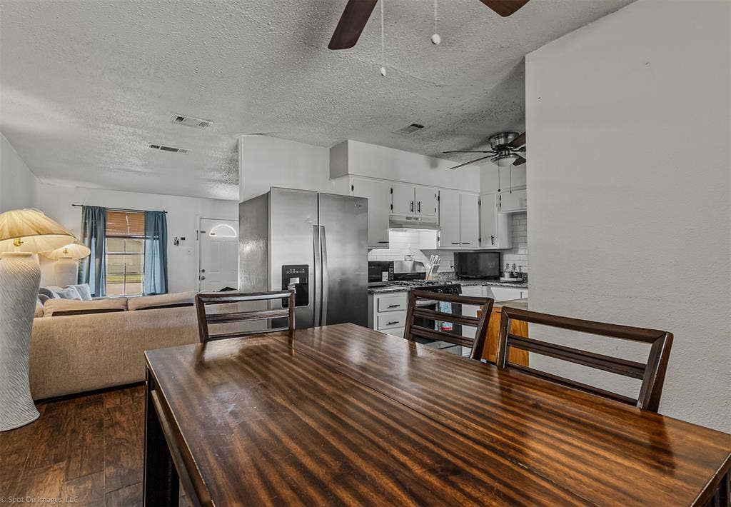 Kitchen featuring white cabinetry, wood-finish flooring, and stainless steel side-by-side refrigerator