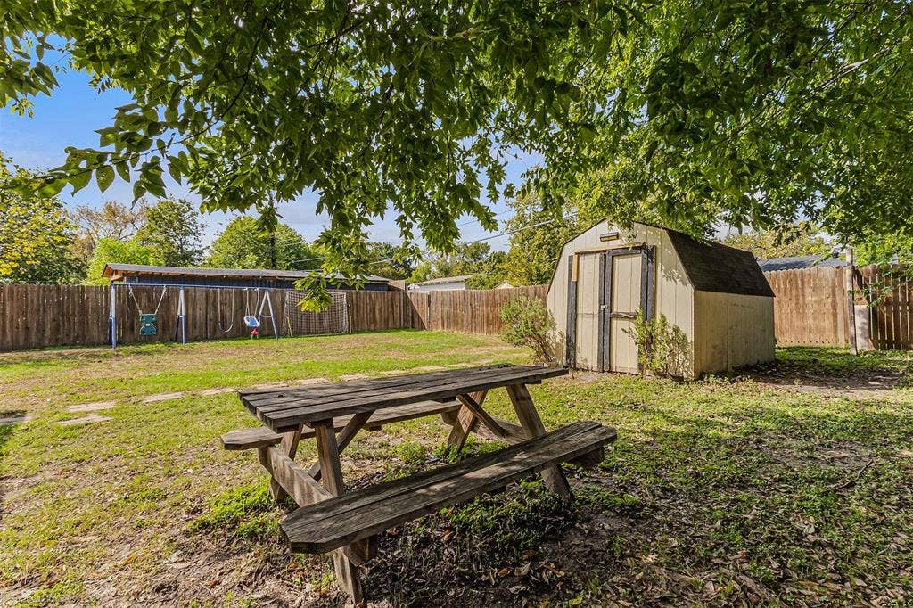 Backyard featuring a wood-panel perimeter fence, storage shed with double doors, and mature tree canopy