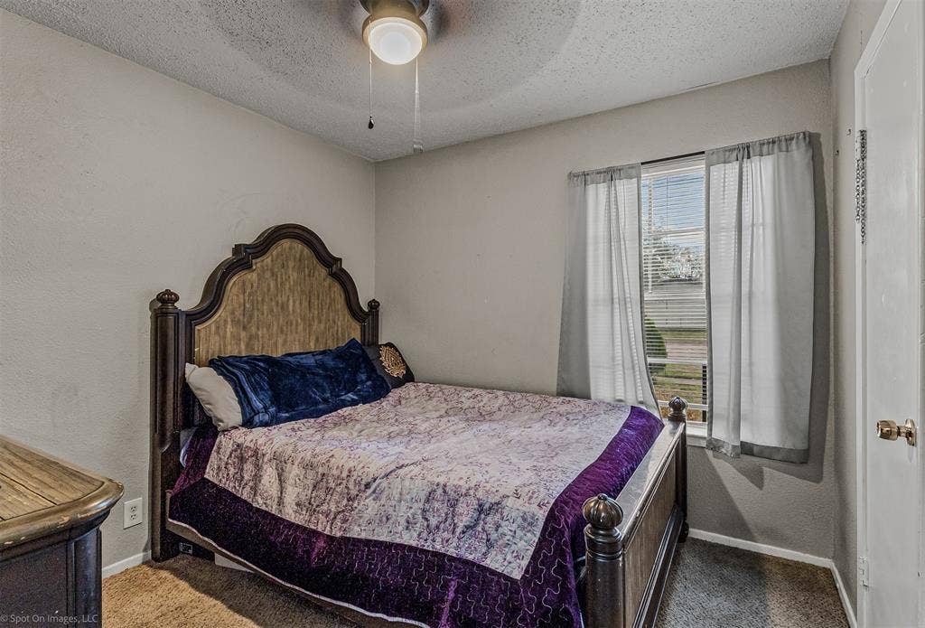 Neutral wall tones, ceiling fan with integrated lighting, window with horizontal blinds, and carpeting