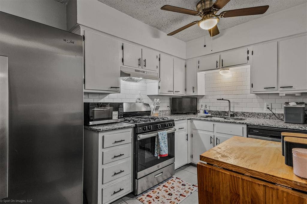 Kitchen featuring stainless steel appliances, stone-look countertops, white shaker-style cabinetry, subway tile backsplash, and a ceiling-mounted light fixture