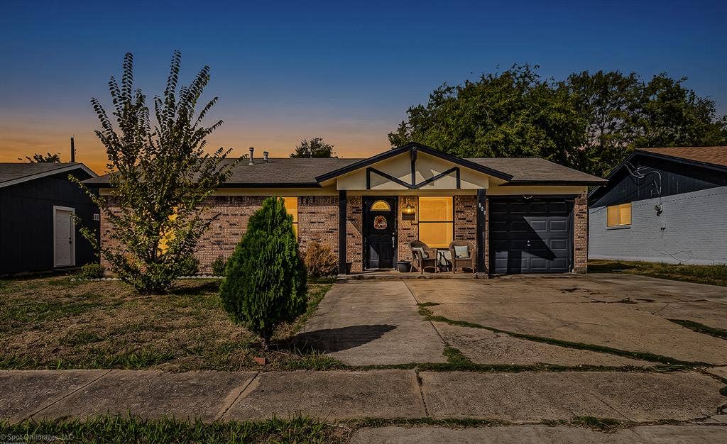 Single-story residence featuring a brick exterior, gabled roofline with timber accents, covered entryway, and attached garage