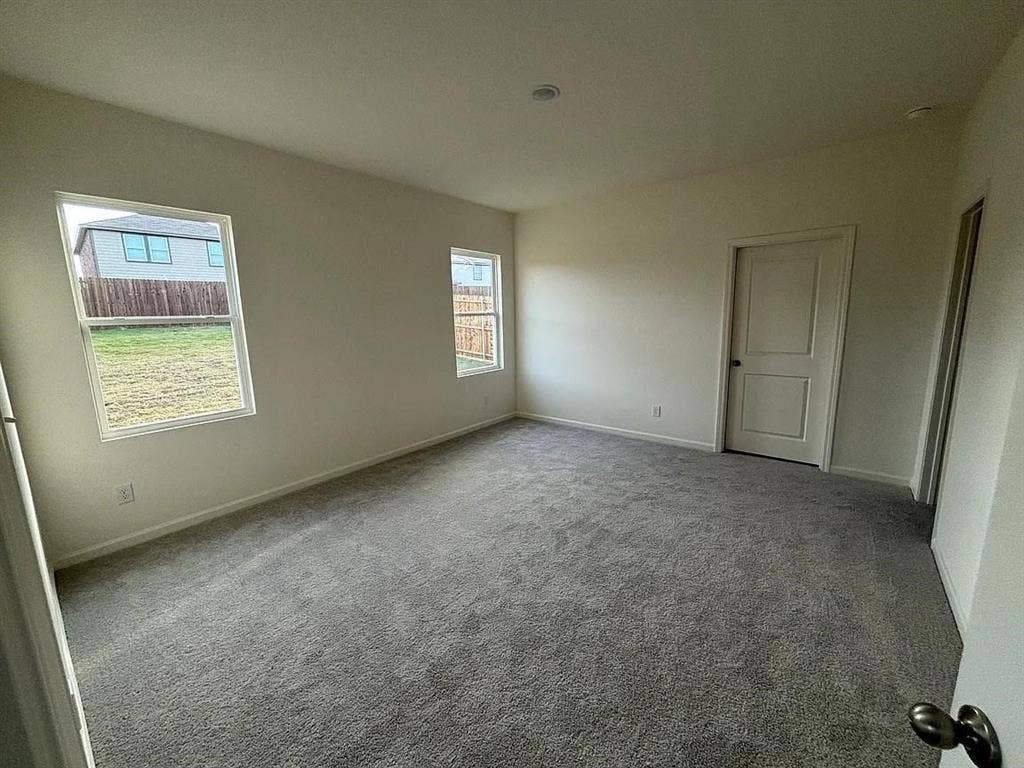 5944 Sahara Drive, Forney, TX 75126 Plush grey carpeting, two rectangular windows, and a panel door with dark hardware