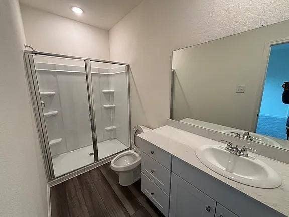 5944 Sahara Drive, Forney, TX 75126 Bathroom featuring a glass-enclosed shower, single vanity with a white countertop, and wood-finish flooring