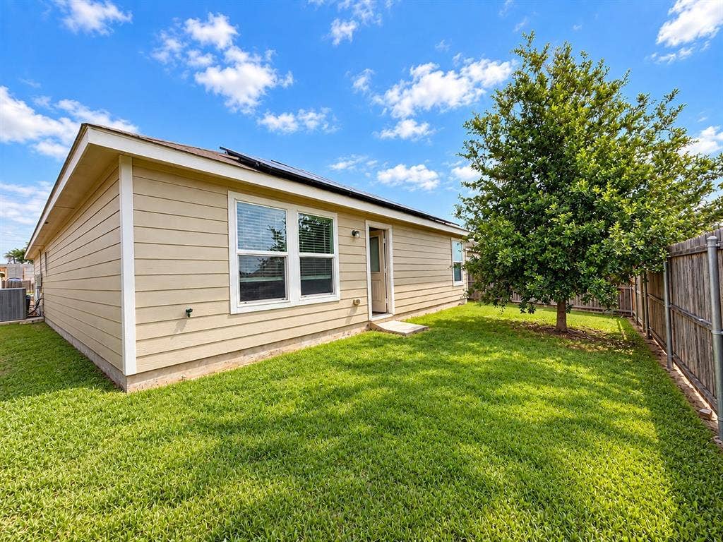 9226 Summerlee Street, Dallas, TX 75227 Expansive backyard featuring a manicured lawn, established tree, and wood privacy fencing