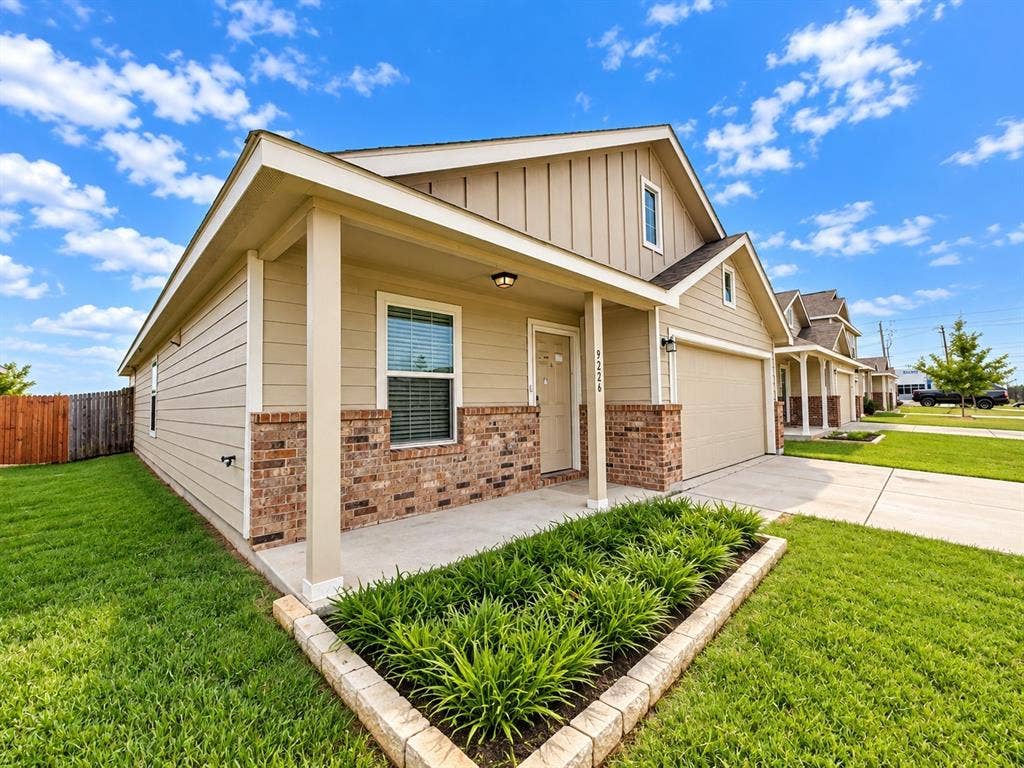 9226 Summerlee Street, Dallas, TX 75227 Siding exterior with brick accents, covered front porch, attached garage, and a landscaped front yard with a planting bed