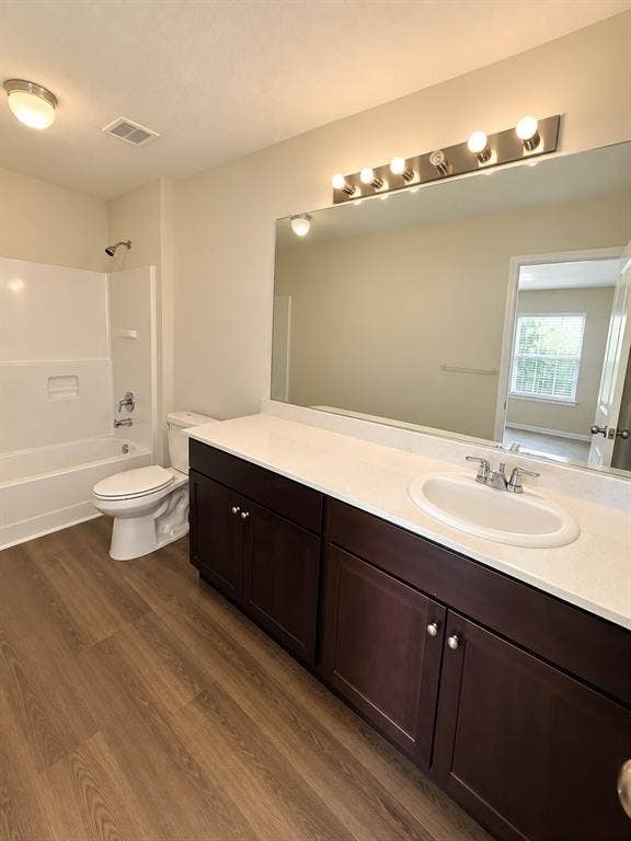 9226 Summerlee Street, Dallas, TX 75227 Wood-finish flooring, white vanity countertop, dark wood-finish cabinetry, single basin sink, and a shower-over-tub combination