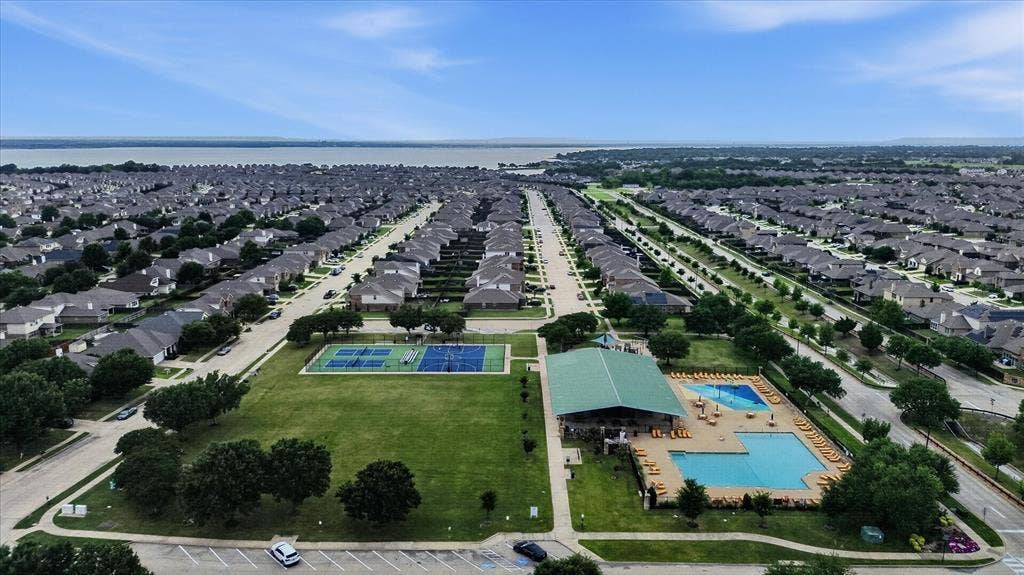 2428 Rosharon Drive, Forney, TX 75126 Aerial view showcasing a master-planned community with tree-lined streets, manicured green spaces, and resort-style amenities including multiple swimming pools and recreational facilities