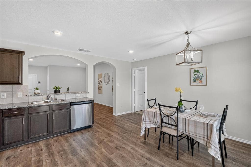 2428 Rosharon Drive, Forney, TX 75126 Wood-finish flooring throughout, dark wood-finish cabinetry, granite-style countertops, stainless-steel dishwasher, and recessed lighting