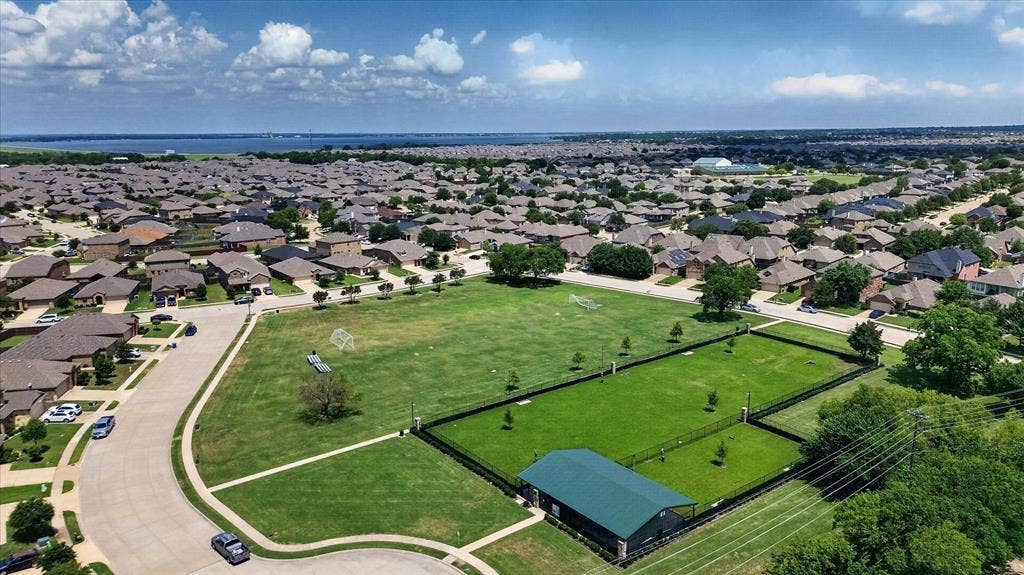 2428 Rosharon Drive, Forney, TX 75126 Expansive neighborhood featuring a large green space, a fenced recreation area with a covered structure, and a broad body of water in the distance