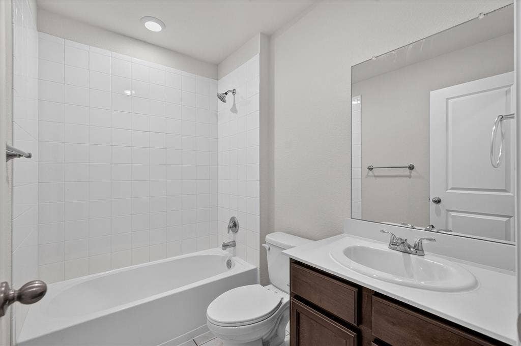 2428 Rosharon Drive, Forney, TX 75126 Bathroom featuring a white subway tile tub surround, recessed lighting, chrome fixtures, a wood-finish vanity, and a large wall-mounted mirror
