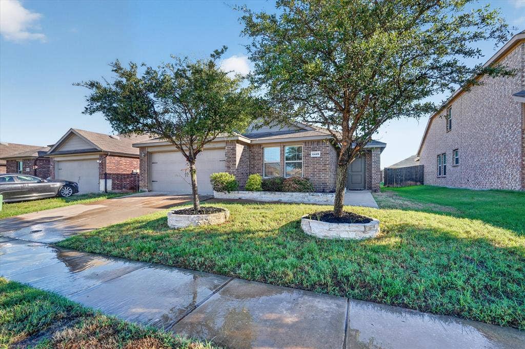 2428 Rosharon Drive, Forney, TX 75126 Brick facade with dual-pane windows, front yard landscaping with mature trees, and an attached two-car garage