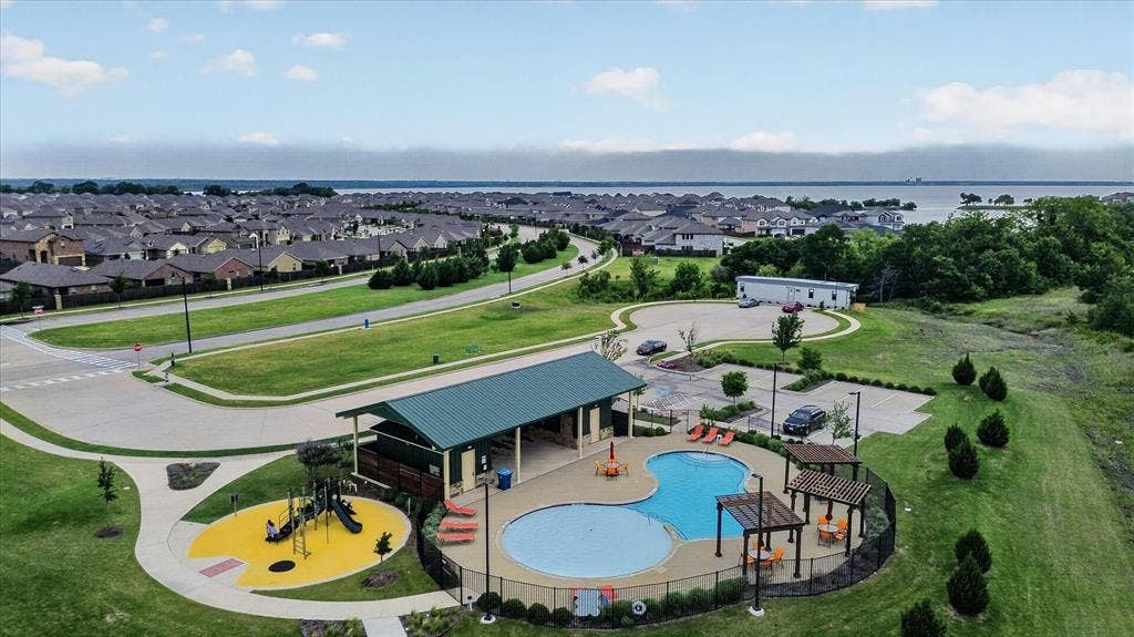 2428 Rosharon Drive, Forney, TX 75126 Expansive residential community featuring a resort-style amenity center with a custom saltwater pool, splash pad with water features, and dedicated play structure set within manicured landscaping