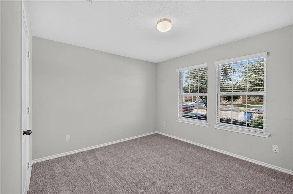 2428 Rosharon Drive, Forney, TX 75126 Neutral wall paint, gray carpet, and two double-hung windows with blinds