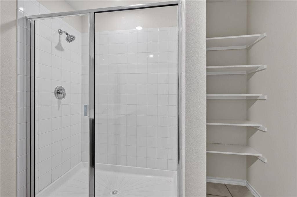 2428 Rosharon Drive, Forney, TX 75126 Modern primary bathroom featuring a frameless glass shower enclosure with chrome fixtures, white subway tile surround, and integrated shower lighting