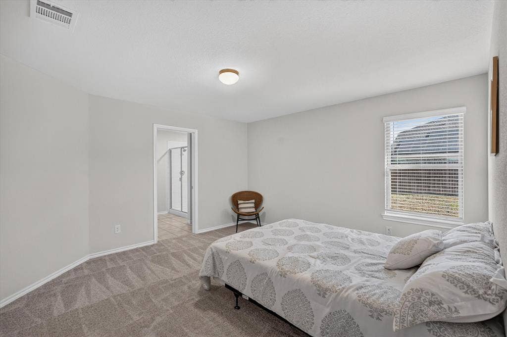 2428 Rosharon Drive, Forney, TX 75126 Spacious bedroom featuring neutral wall finishes, abundant natural light from a large window with blinds, wood-finish flooring with carpet inlay, and a ceiling-mounted light fixture