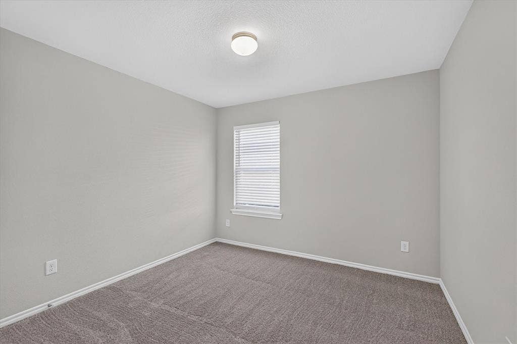 2428 Rosharon Drive, Forney, TX 75126 Bright secondary bedroom featuring neutral wall finishes, carpet flooring, a generous window with plantation shutters providing natural light, and recessed ceiling lighting