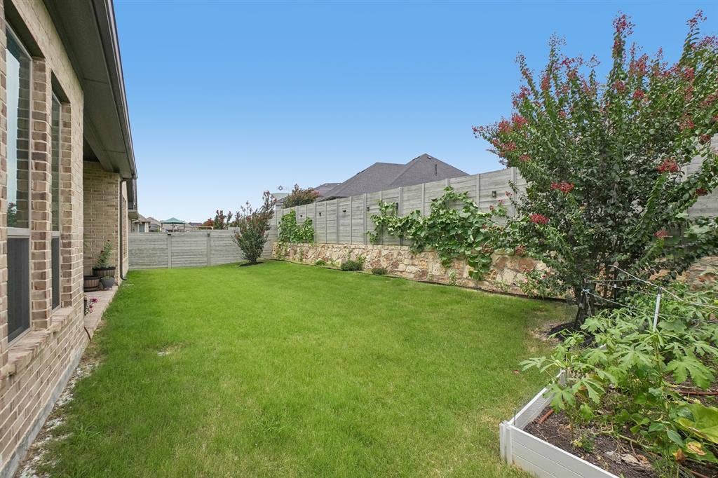 Expansive lawn area with a raised garden bed and a mature flowering tree