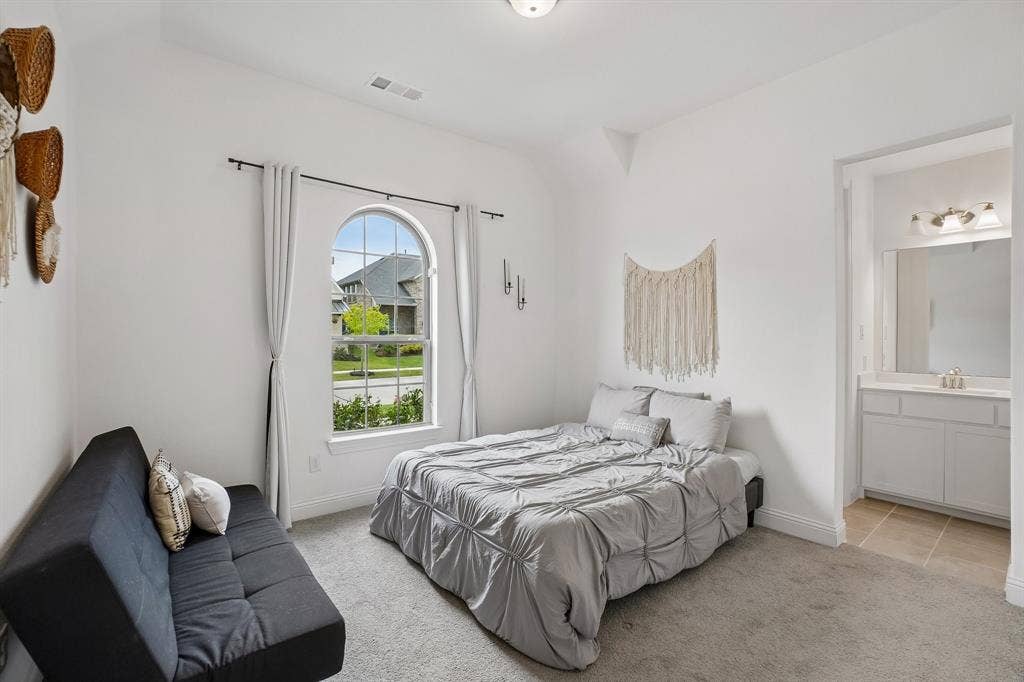 Arched window with exterior streetscape, sconce lighting, recessed ceiling light, and access to a bathroom featuring a vanity with a mirror and brushed nickel fixture
