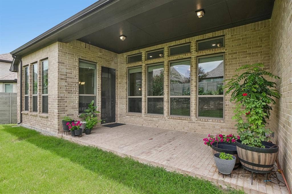 Covered patio featuring brick construction, a screened door, and multiple windows