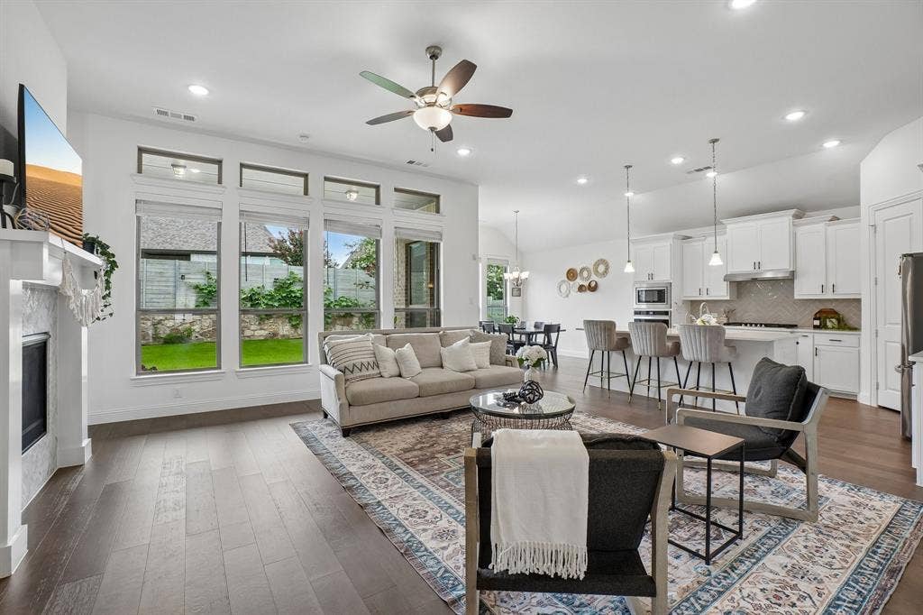 Open-concept living area with wood-finish flooring, a contemporary fireplace, and abundant natural light from multiple windows