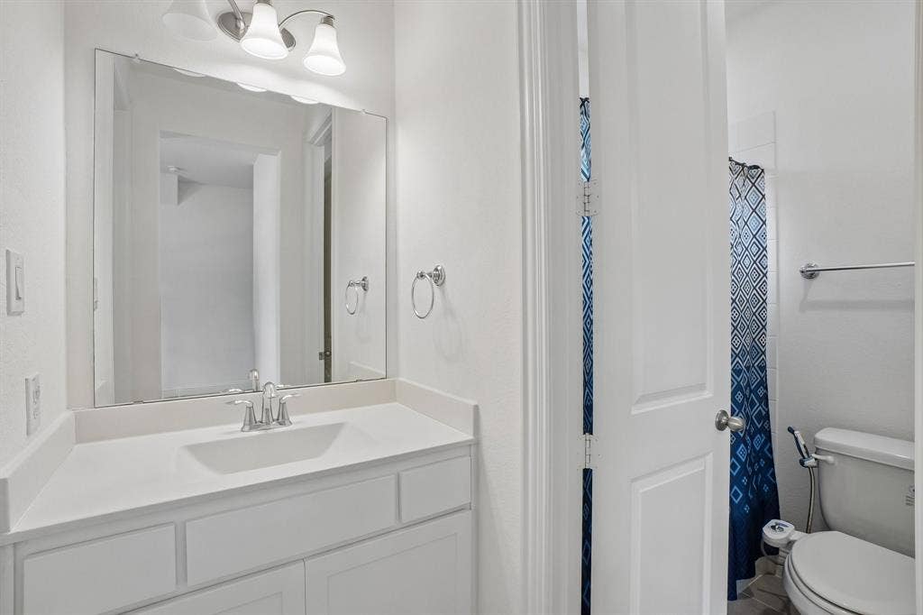 White vanity with shaker-style cabinetry, an undermount sink, and a light-toned countertop