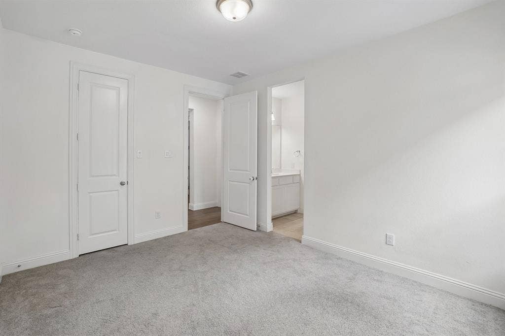 Neutral-toned carpet flooring, white walls, and bright overhead lighting