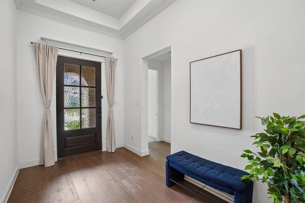 Dark wood-finish entry door with multiple glass panes, wood-finish flooring, and crown molding