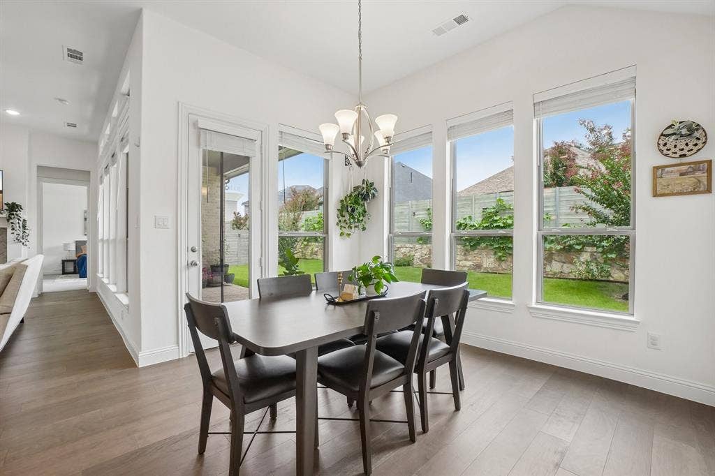 Vaulted ceiling, wood-finish flooring, multiple large windows, glass-paneled exterior door, recessed lighting