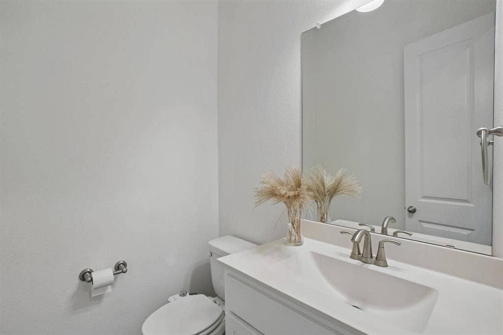 Vanity with an integrated sink, brushed nickel faucet, mirror, and overhead lighting