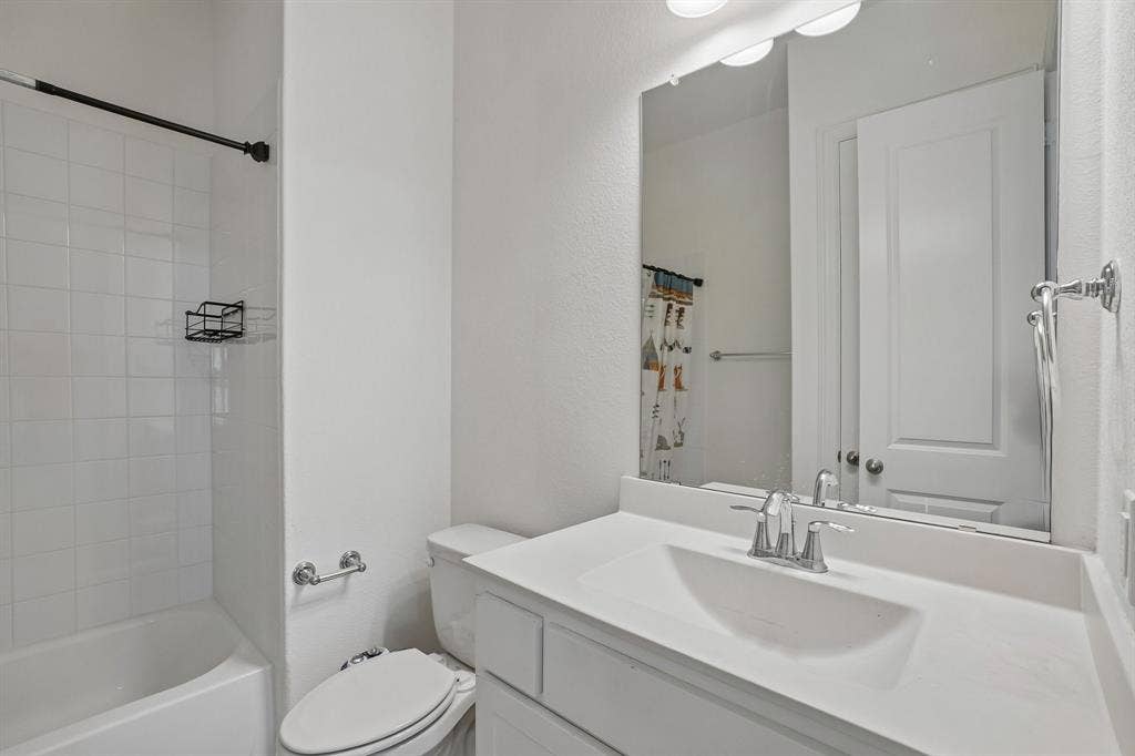 Bathroom featuring a tub/shower combination, white tile surround, single vanity with integrated sink, and chrome fixtures