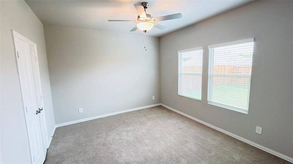 505 Blanton Street, McKinney, TX 75069 Spacious room with neutral wall tones, carpeted flooring, two windows with blinds, and a ceiling fan with integrated lighting